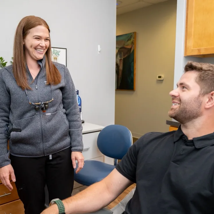 Lumon Dental dentist talking with a smiling patient in the operatory